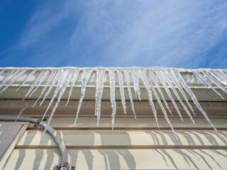 frozen gutters with long icicles hanging from ice dams